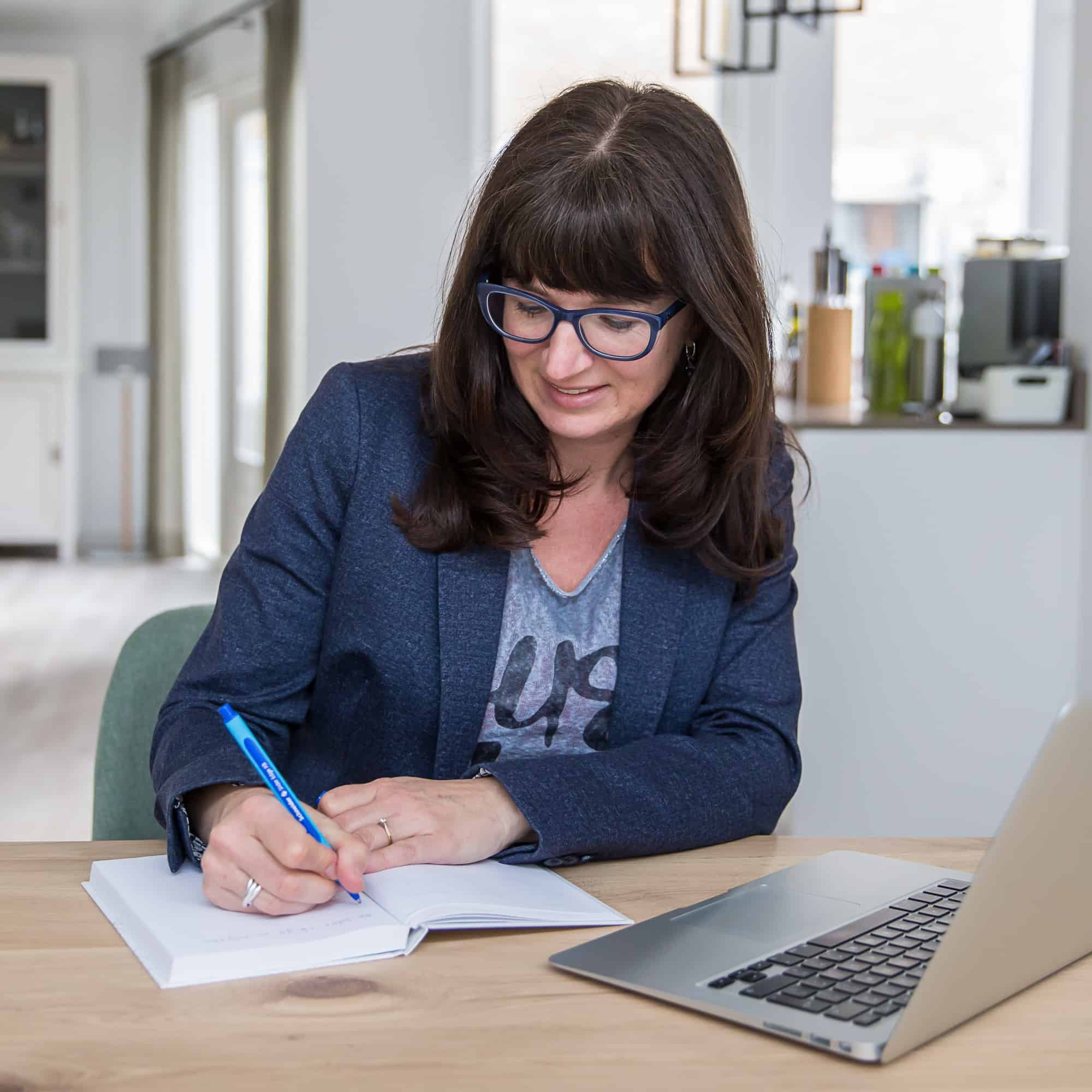 Portretfoto van Marja Verheijen, naar beneden kijkend en schrijvend in notitieboek, op de Homepage bij Beleid, van mavadvieseninterim.nl