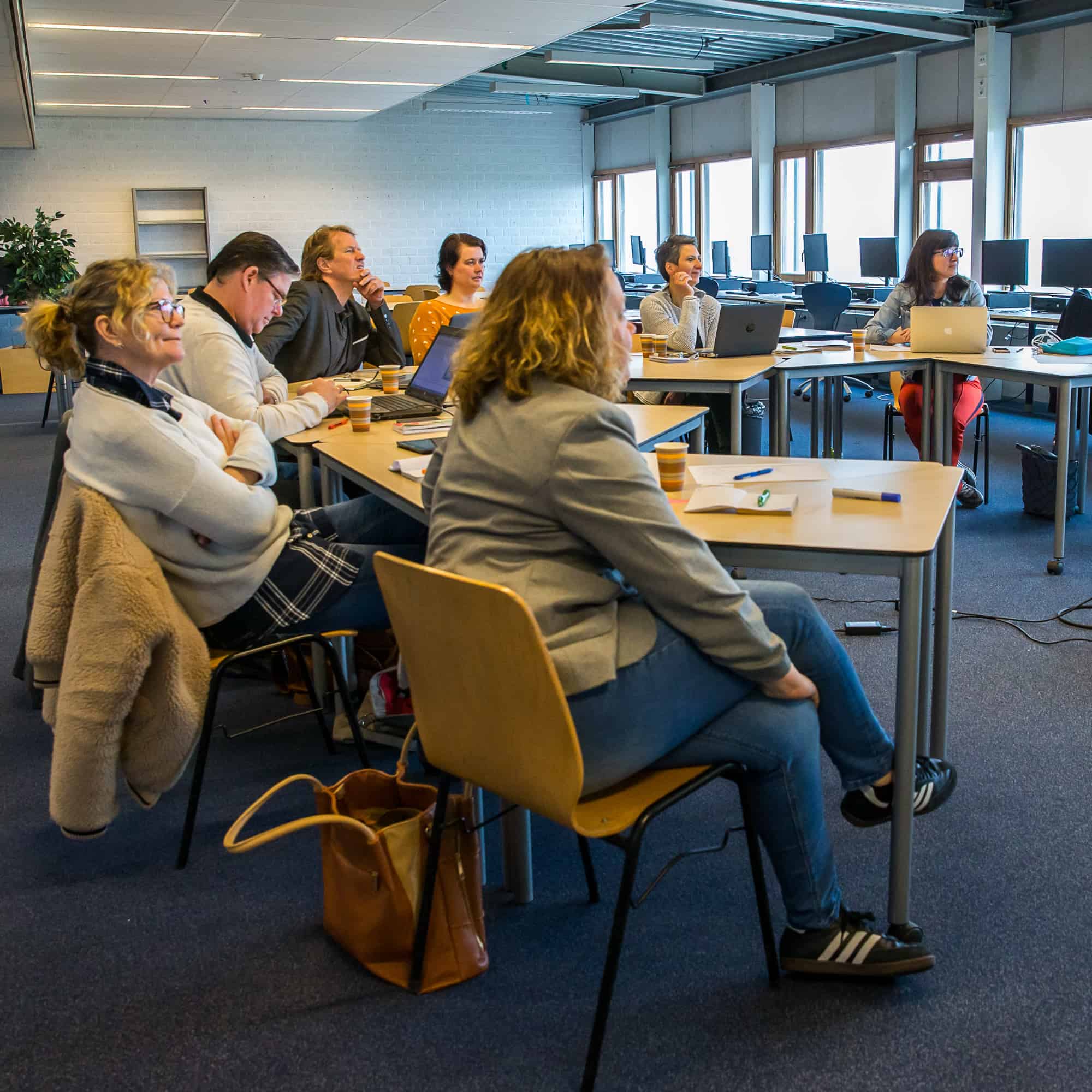 Foto van een luisterend groepje mensen, zittend achter tafels, op de Homepage bij Onderwijs, van mavadvieseninterim.nl