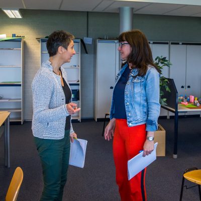 Foto van Marja Verheijen, staand in overleg met 1 andere persoon, op de pagina Onderwijs van mavadvieseninterim.nl